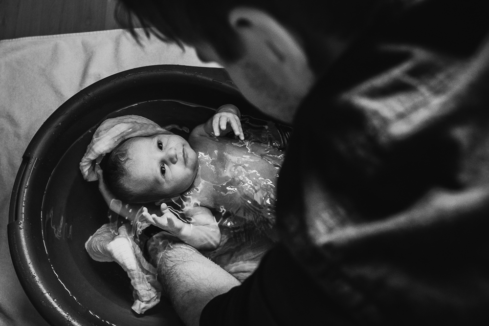 Baby wird von Papa während einer Wochenbettreportage gebadet